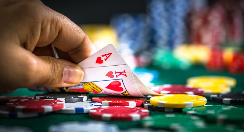 Gambling Hand Holding Poker Cards and Money Coins Chips